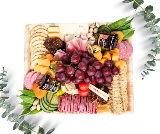 Charcuterie Host board on a bamboo tray with cured meat, cheese, vegetables, fresh fruit, nuts, dried fruit, crackers, honey or preserves, pickled items and sweet treats. Serves 4.