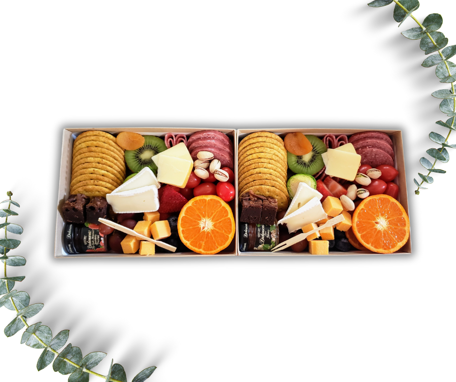 Gourmet food box with assorted snacks, fruits, and cheeses on a white background.