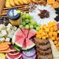 large grazing board with meats cheeses crackers fruit and nuts