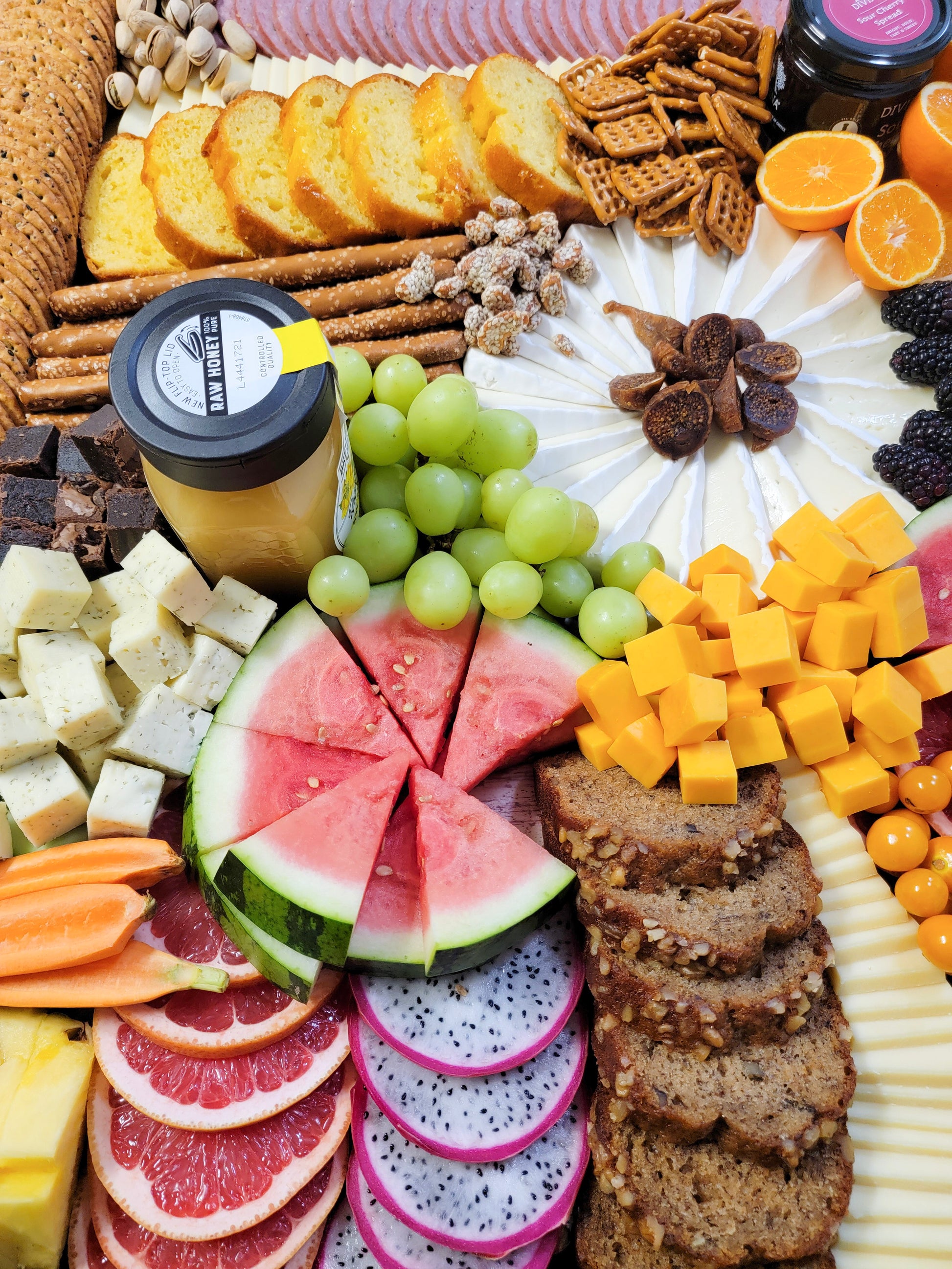 large grazing board with meats cheeses crackers fruit and nuts