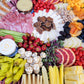 Assorted meats, cheeses, fruits, and vegetables arranged on a platter.