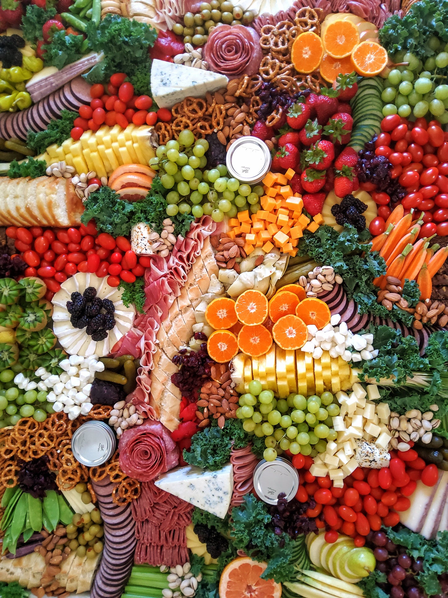 Large charcuterie board filled with assorted meats, cheeses, fruits, and crackers for a large event
